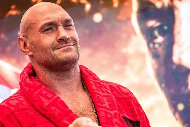 Tyson Fury in a red robe smiling at a press event